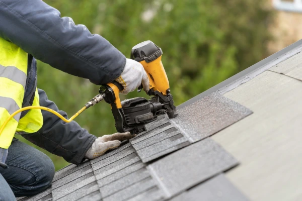 Crandall Roofing professional installing asphalt shingles with a nail gun during a residential roof replacement