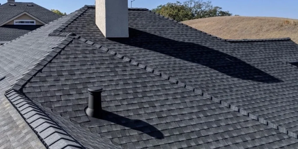 Newly installed dark charcoal asphalt shingle roof on a Sonoma County home with chimney and rooftop ventilation
